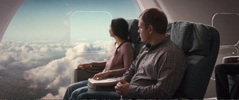 Movie still from “Downsizing” (2017), directed by Alexander Payne – A man and a woman sitting on a plane looking out a window; Medium shot, High angle