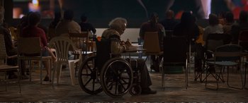 Movie still from “Downsizing” (2017), directed by Alexander Payne – An old man in a wheelchair writing on a piece of paper; Wide shot, High angle