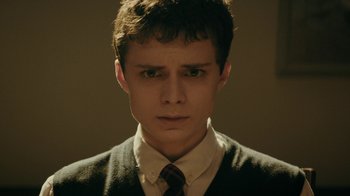 A young man in a suit and tie looking at the camera