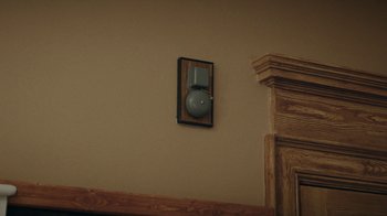 Movie still from “Dr. Bird's Advice for Sad Poets” (2021), directed by Yaniv Raz – An electrical box mounted on the wall above a fireplace; Extreme Close Up shot, Low angle
