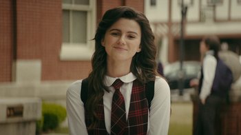 A woman with long brown hair wearing a plaid tie