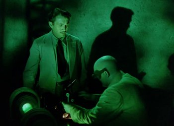 Movie still from “Dr. Cyclops” (1940), directed by Ernest B. Schoedsack – A man smoking a cigarette in a dark room; Medium shot, Low angle