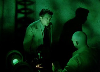 Movie still from “Dr. Cyclops” (1940), directed by Ernest B. Schoedsack – A man in a suit and tie standing next to another man in a suit and tie; Medium shot, Over the shoulder angle