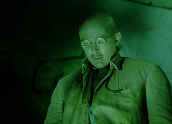 Movie still from “Dr. Cyclops” (1940), directed by Ernest B. Schoedsack – A man with glasses is standing in the dark; Medium shot, Low angle