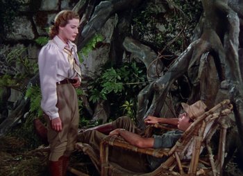 Movie still from “Dr. Cyclops” (1940), directed by Ernest B. Schoedsack – A woman standing next to a man laying in a chair; Wide shot, High angle