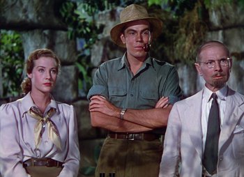 Movie still from “Dr. Cyclops” (1940), directed by Ernest B. Schoedsack – A group of people standing next to each other in front of a stone wall; Medium shot, Low angle