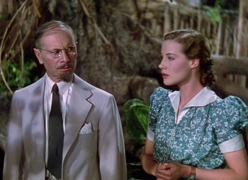 Movie still from “Dr. Cyclops” (1940), directed by Ernest B. Schoedsack – A man and a woman standing next to each other in front of trees; Medium shot, Low angle