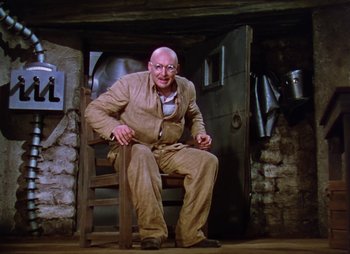 Movie still from “Dr. Cyclops” (1940), directed by Ernest B. Schoedsack – An old man sitting in a chair in a room; Wide shot, High angle