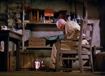 Movie still from “Dr. Cyclops” (1940), directed by Ernest B. Schoedsack – A man sitting in a chair in front of a table; Wide shot, Low angle