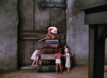 Movie still from “Dr. Cyclops” (1940), directed by Ernest B. Schoedsack – A group of people standing on top of a pile of books; Wide shot, High angle