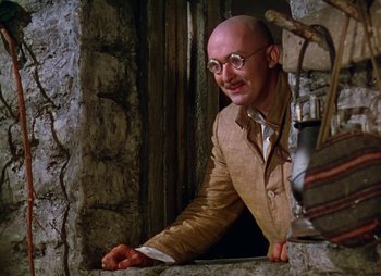 Movie still from “Dr. Cyclops” (1940), directed by Ernest B. Schoedsack – A bald man in a tan jacket and glasses; Medium shot, Low angle