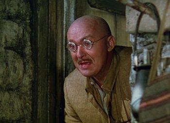 Movie still from “Dr. Cyclops” (1940), directed by Ernest B. Schoedsack – A bald man wearing glasses and a tan jacket; Close Up shot, Low angle