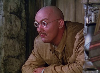 Movie still from “Dr. Cyclops” (1940), directed by Ernest B. Schoedsack – A bald man wearing glasses and a tan jacket; Close Up shot, Low angle