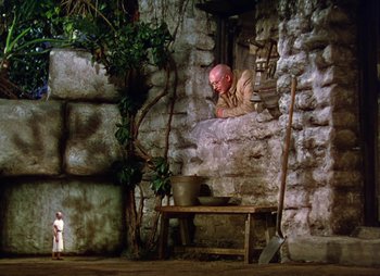 Movie still from “Dr. Cyclops” (1940), directed by Ernest B. Schoedsack – An old man leaning on a stone wall in a cave; Wide shot, Low angle