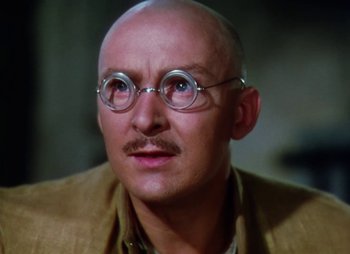 Movie still from “Dr. Cyclops” (1940), directed by Ernest B. Schoedsack – A bald man wearing glasses and a tan jacket; Close Up shot, Low angle