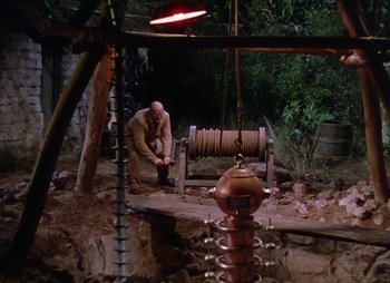Movie still from “Dr. Cyclops” (1940), directed by Ernest B. Schoedsack – A man working on an outdoor structure in the woods; Wide shot, High angle