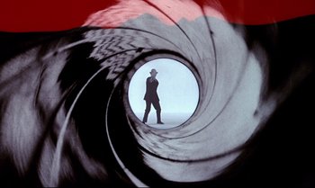 Movie still from “Dr. No” (1962), directed by Terence Young – A man is standing inside of a gun barrel; Wide shot, Low angle