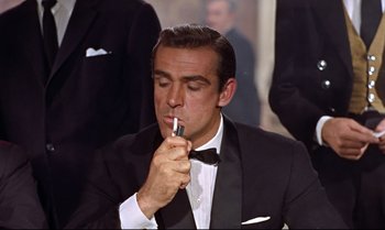 Movie still from “Dr. No” (1962), directed by Terence Young – Sean connery smoking a cigarette while wearing a tuxedo; Close Up shot, Low angle