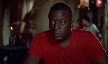 Movie still from “Dr. No” (1962), directed by Terence Young – A person wearing a red t - shirt; Close Up shot, Over the shoulder angle