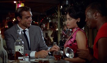 Movie still from “Dr. No” (1962), directed by Terence Young – A man and a woman sitting at a table in front of each other; Medium shot, Over the shoulder angle