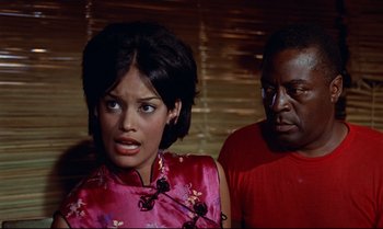 Movie still from “Dr. No” (1962), directed by Terence Young – A woman in a pink dress and a man in a red shirt; Medium shot, Over the shoulder angle