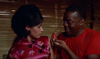 Movie still from “Dr. No” (1962), directed by Terence Young – A man and a woman eating a piece of fruit; Close Up shot, High angle