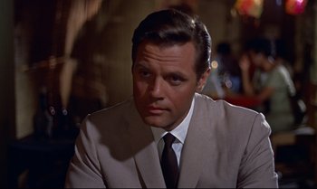 Movie still from “Dr. No” (1962), directed by Terence Young – A person wearing a suit and tie; Close Up shot, Over the shoulder angle