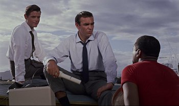 Movie still from “Dr. No” (1962), directed by Terence Young – A man sitting on the ground holding a baseball bat; Medium shot, Low angle