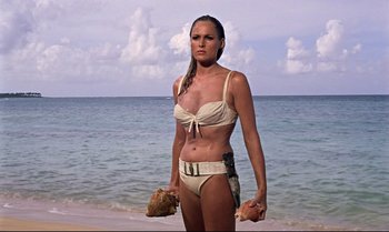 Movie still from “Dr. No” (1962), directed by Terence Young – A beautiful woman in a white bikini on the beach; Medium shot, Low angle