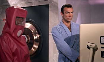 Movie still from “Dr. No” (1962), directed by Terence Young – Sean connery as james bond in a bathrobe in front of a mirror; Medium shot, Over the shoulder angle