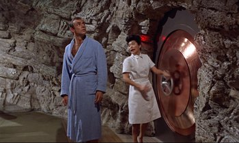 Movie still from “Dr. No” (1962), directed by Terence Young – A man and a woman are playing frisbee in a cave; Wide shot, High angle