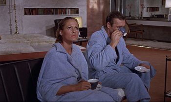 Movie still from “Dr. No” (1962), directed by Terence Young – A man and a woman sitting on a couch drinking coffee; Medium shot, High angle