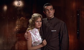 Movie still from “Dr. No” (1962), directed by Terence Young – A man and a woman posing for a picture; Medium shot, Low angle
