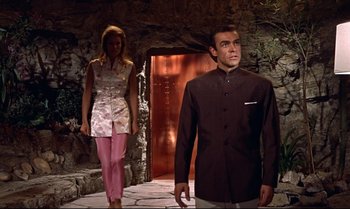 Movie still from “Dr. No” (1962), directed by Terence Young – A man and a woman standing in front of an entrance to a cave; Medium shot, Low angle