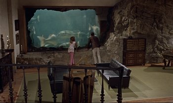 Movie still from “Dr. No” (1962), directed by Terence Young – A man and a girl looking at a fish tank in an aquarium; Wide shot, High angle