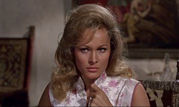 Movie still from “Dr. No” (1962), directed by Terence Young – A beautiful woman with long blonde hair wearing a pink and white top; Close Up shot, High angle