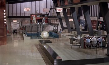 Movie still from “Dr. No” (1962), directed by Terence Young – An airport terminal filled with lots of people; Extreme Wide shot, High angle