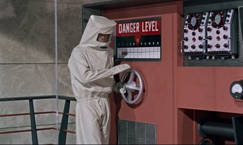 Movie still from “Dr. No” (1962), directed by Terence Young – A man in a white suit and a white mask is fixing a sign; Wide shot, Low angle
