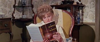 Movie still from “Dr. Who and the Daleks” (1965), directed by Gordon Flemyng – A woman sitting in a chair while reading a book; Medium shot, High angle
