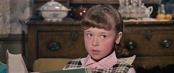 Movie still from “Dr. Who and the Daleks” (1965), directed by Gordon Flemyng – A young girl sitting on a couch holding a book; Close Up shot, High angle