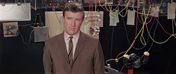 Movie still from “Dr. Who and the Daleks” (1965), directed by Gordon Flemyng – A man wearing a suit and tie standing in front of wires; Close Up shot, Low angle