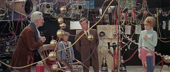 Movie still from “Dr. Who and the Daleks” (1965), directed by Gordon Flemyng – A man and a woman standing next to each other in a room; Medium shot, High angle