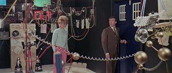 Movie still from “Dr. Who and the Daleks” (1965), directed by Gordon Flemyng – A man and a woman standing next to each other; Medium shot, Low angle