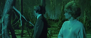 Movie still from “Dr. Who and the Daleks” (1965), directed by Gordon Flemyng – A man in a suit and tie standing next to another man in a suit and tie; Medium shot, Over the shoulder angle