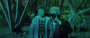 Movie still from “Dr. Who and the Daleks” (1965), directed by Gordon Flemyng – An older man and a young boy looking through binoculars; Medium shot, Over the shoulder angle