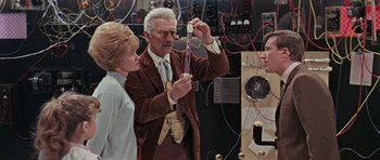 Movie still from “Dr. Who and the Daleks” (1965), directed by Gordon Flemyng – An older man and two young women in an electrical lab; Medium shot, Over the shoulder angle