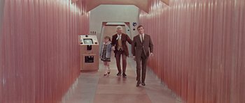 Movie still from “Dr. Who and the Daleks” (1965), directed by Gordon Flemyng – Two men and a little girl walking down a hall way; Wide shot, High angle