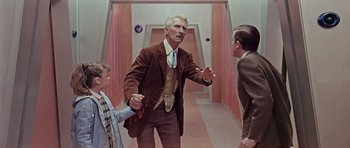 Movie still from “Dr. Who and the Daleks” (1965), directed by Gordon Flemyng – An older man in a suit and tie talking to two young men; Medium shot, Over the shoulder angle