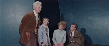 Movie still from “Dr. Who and the Daleks” (1965), directed by Gordon Flemyng – A group of people sitting on top of a wall; Medium shot, Low angle