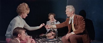 Movie still from “Dr. Who and the Daleks” (1965), directed by Gordon Flemyng – An older man and a young girl are sitting on the ground; Medium shot, High angle